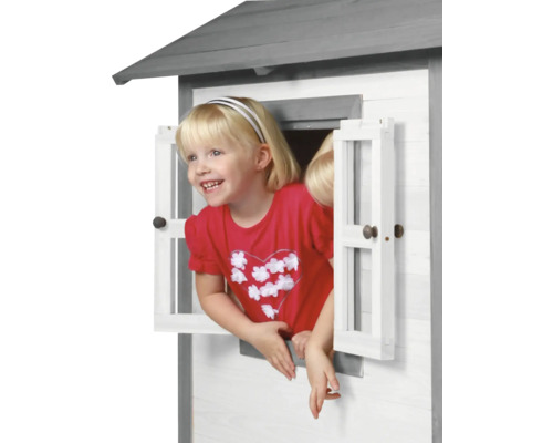 Meisje kijkt uit het raam van een houten speelhuis