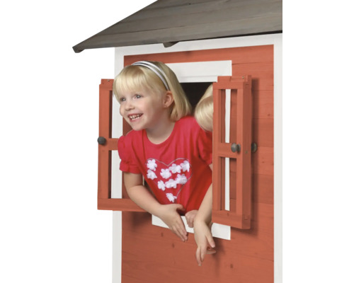 Meisje kijkt uit het raam van een houten speelhuis