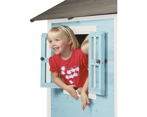 Meisje kijkt uit het raam van een houten speelhuis.