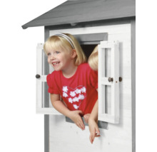 Meisje kijkt uit het raam van een houten speelhuis