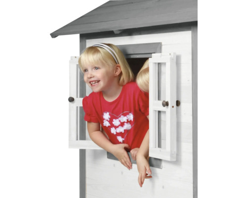 Meisje kijkt uit het raam van een houten speelhuis