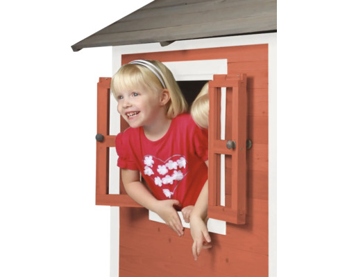 Meisje kijkt uit het raam van een houten speelhuisje