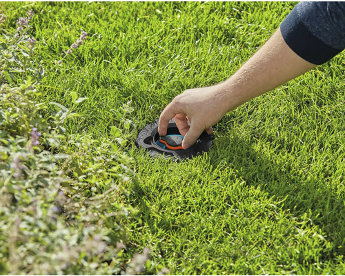 Een persoon past een verzonken gazonsproeier aan in het gazon.
