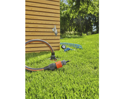 Tuinscene met kraan, tuinslang en verbindingsstuk op gazon