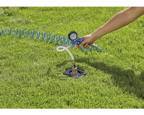 Een in het gazon geïnstalleerde sprinklerinstallatie wordt gecontroleerd met een persluchttester.