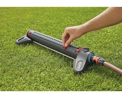 Gardena sproeier op gazon met hand op rode regelaar