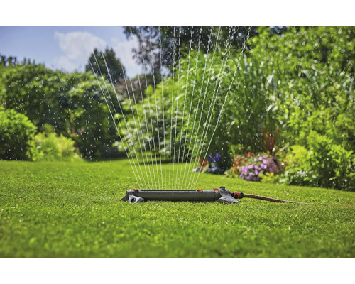 Sproeier besproeit gazon in de tuin