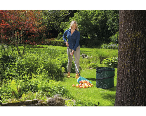 Vrouw verzamelt appels met een fruitplukker in een tuin
