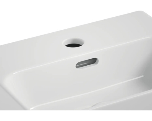 Detailopname van een witte keramische wastafel met kraangat en overloop