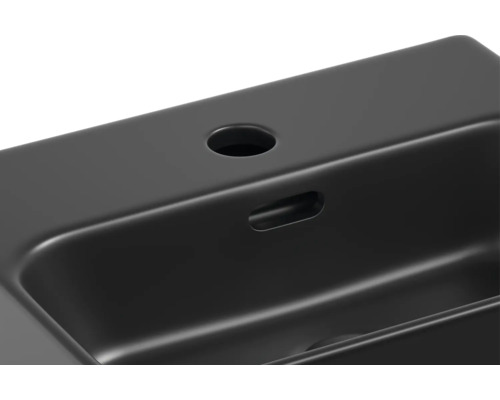 Detailopname van een zwarte wastafel met kraangat en overloop