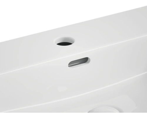 Detailopname van een wastafel met kraangat en overloop