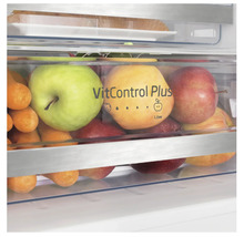 Close-up van een groentelade van een koelkast gevuld met appels en wortelen