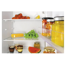 Interieurbeeld van een koelkast met voedingsmiddelen zoals tomaten, druiven, watermeloen en glazen met desserts