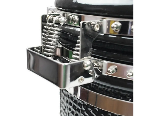Detailopname van een kamado grill met zilverkleurige metalen fittingen en een veermechanisme
