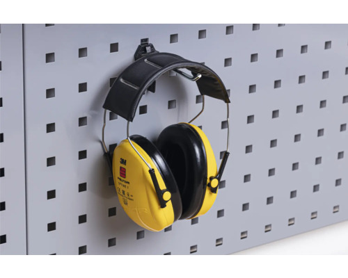 Gele 3M Peltor Optime I oorkappen hangen aan een wand met gaten
