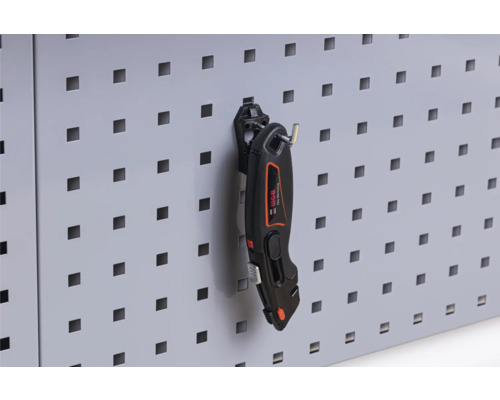 Geperforeerde wand met een cuttermes voor werkplaatsbenodigdheden
