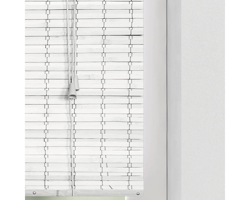 Witte bamboe jaloezie aan het raam