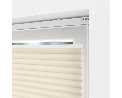 Close-up van een beige plisségordijn voor het raam