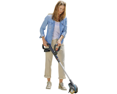 Vrouw gebruikt een accu voegenreiniger in de tuin.