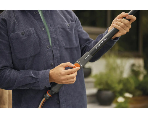 Persoon regelt tuinslang op een telescopische lans