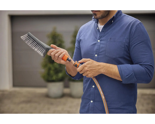 Man sluit borstel aan op tuinslang