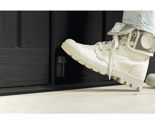 Persoon opent met de voet een zwarte buitendeur met draaiknop