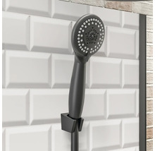 Handdouche in badkamer met witte tegels op de achtergrond.