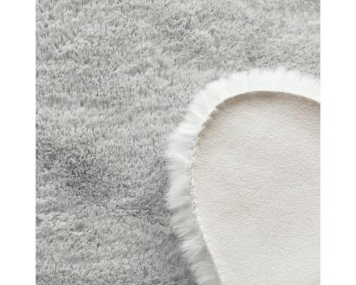 Detailopname van een rond, lichtgrijs vloerkleed met lange pool