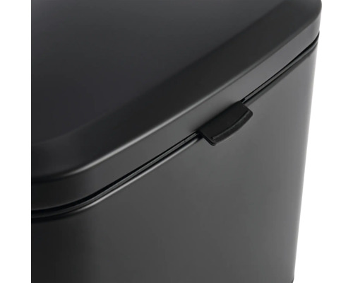 Detail van een zwarte afvalemmer met deksel en sluitmechanisme.