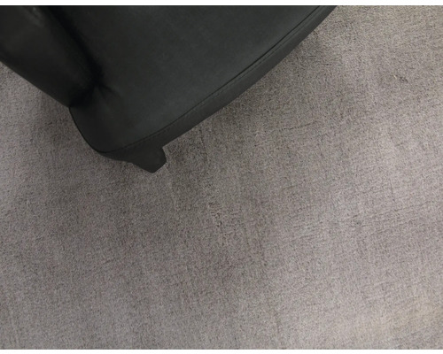 Detailopname van een zwarte fauteuil op een grijs tapijt