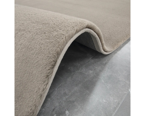 Detailweergave van een beige tapijt met hoogpolig oppervlak.