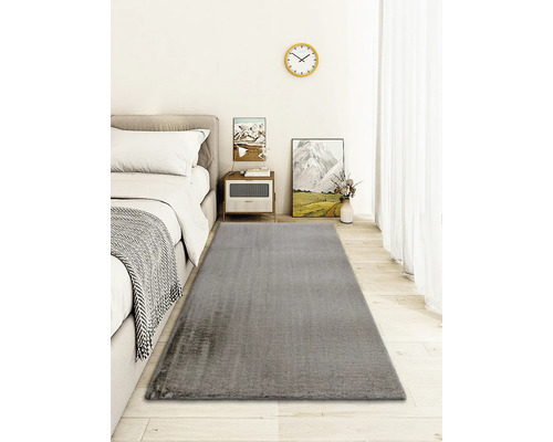 Grijs tapijt in een slaapkamer met bed en bijzettafel