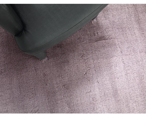 Close-up van een lila tapijt met een deel van een fauteuil