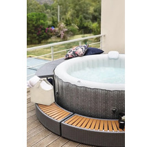 Opblaasbare jacuzzi met rotan omranding op een terras met kussens en handdoeken