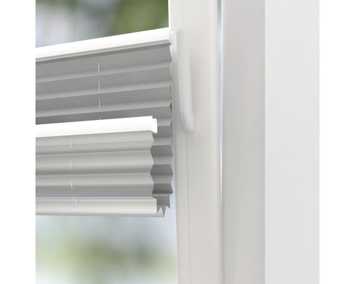 Close-up van een wit plisségordijn op een raam