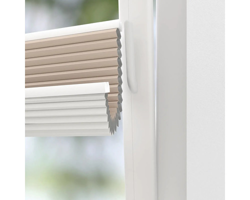 Close-up van een beige en wit plisségordijn in een raam