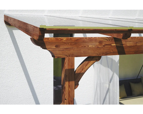 Detail van een houten pergola met transparant dak, bevestigd aan een huis
