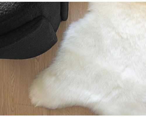 Witte kunstvacht tapijt naast een fauteuil