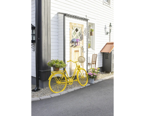 Decoratieve gele fiets met bloemen voor een huis.