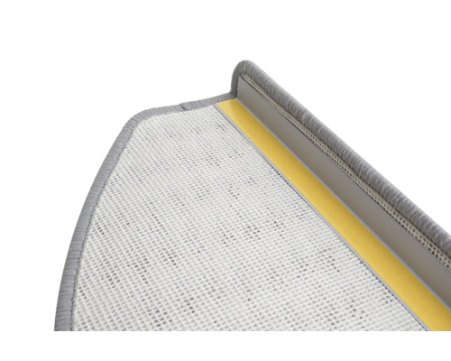Detailopname van een grijze traptrede met textieloppervlak en plakstrips voor bevestiging.