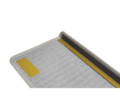 Detailopname van een grijze trapmat met plakstrip voor bevestiging.
