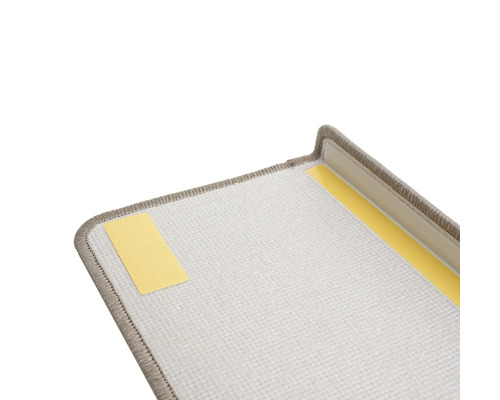 Detailweergave van een traptrede met tapijt en plakstrips voor bevestiging.