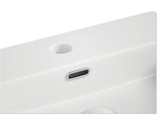 Detail van een witte wastafel met overloop