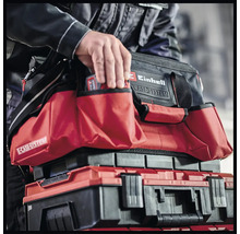 Een man grijpt in een Einhell gereedschapstas die op een Einhell gereedschapskist staat.