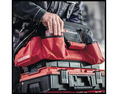 Een man grijpt in een Einhell gereedschapstas die op een Einhell gereedschapskist staat.