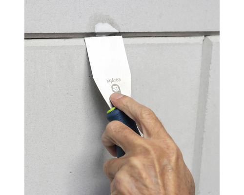 Een man gebruikt een plamuurmes om een voeg tussen twee panelen af te dichten.