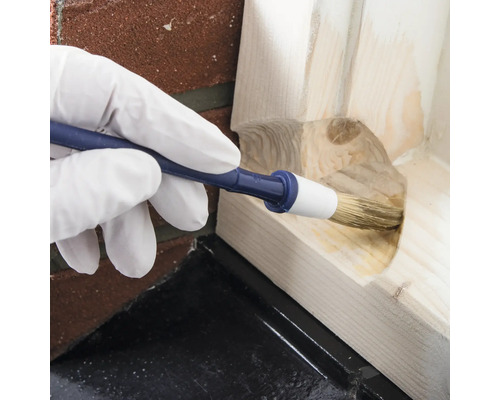 Persoon draagt handschoenen en gebruikt borstel voor houtbewerking