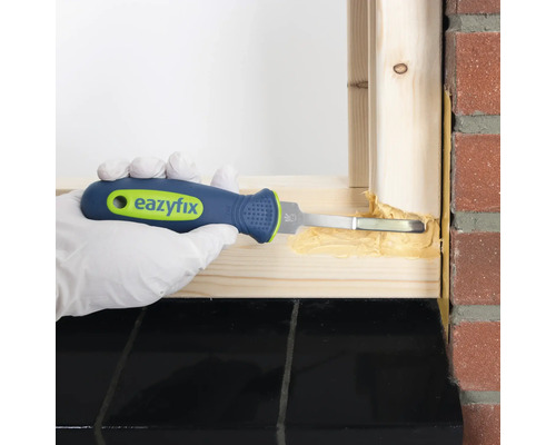 Hand met handschoen gebruikt een voegschrapergereedschap om voegmiddel te verwijderen