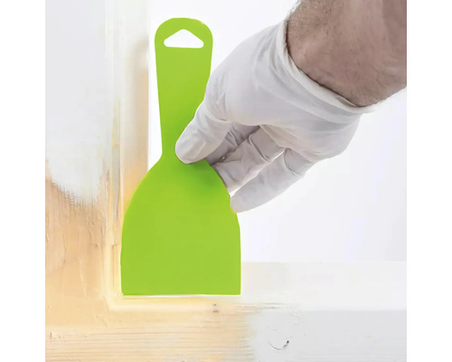 Persoon met handschoen gebruikt een plamuurmes