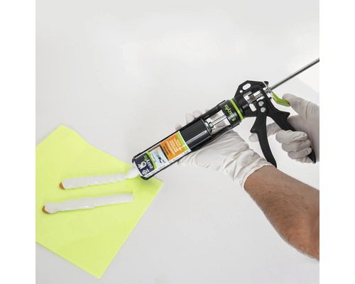 Een kitpistool wordt bediend door handen met beschermende handschoenen om afdichtmiddel aan te brengen.